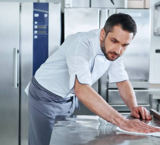 Bearded man prepares the surface for cooking in the kitchen. Cook carefully wipes the surface. Health and safety concept.