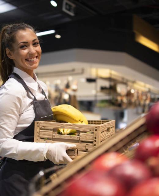 Supermarket worker supplying fruit department with food.